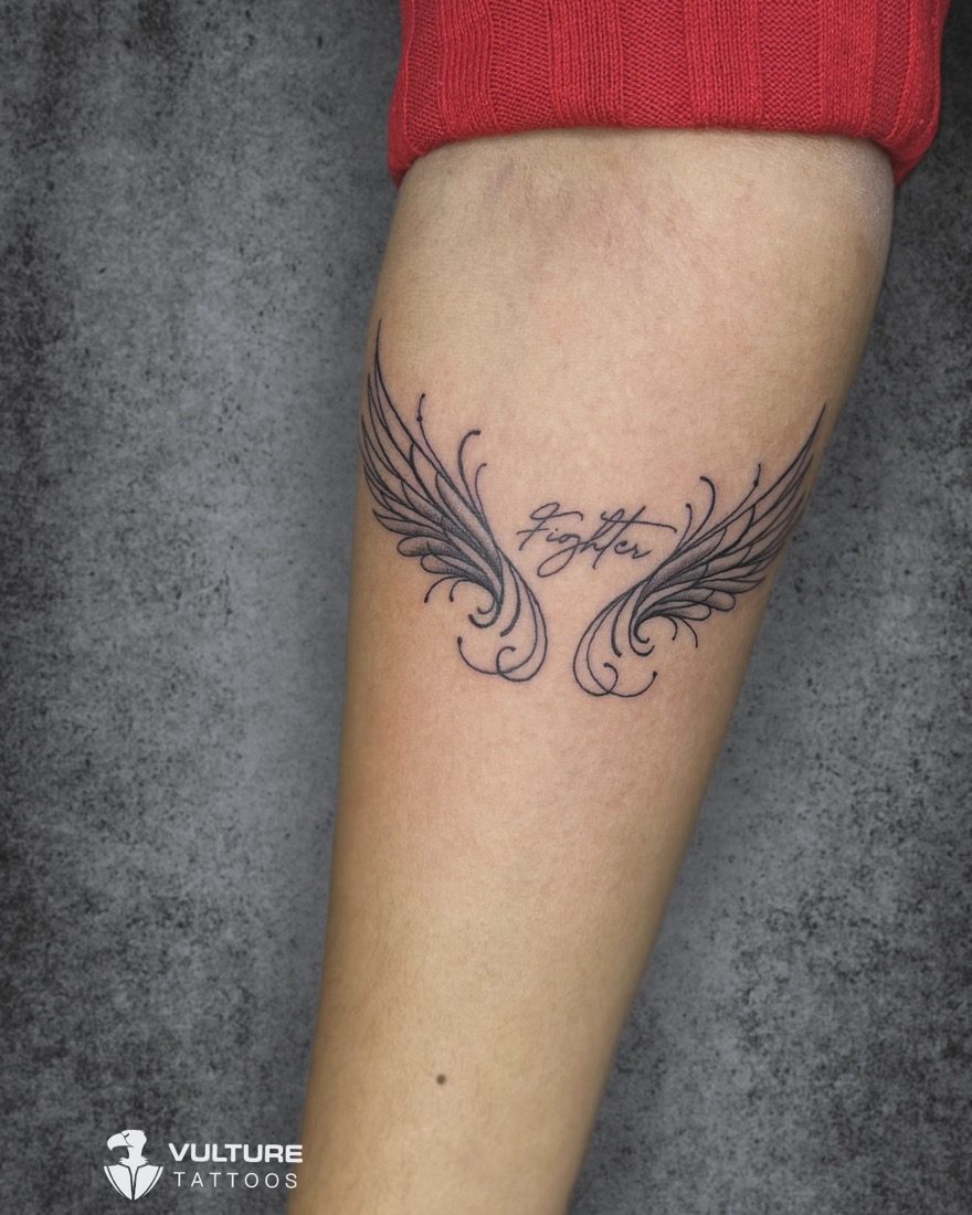 Fighter Script With Wings — tattoo by Vulture Tattoos, Gurugram