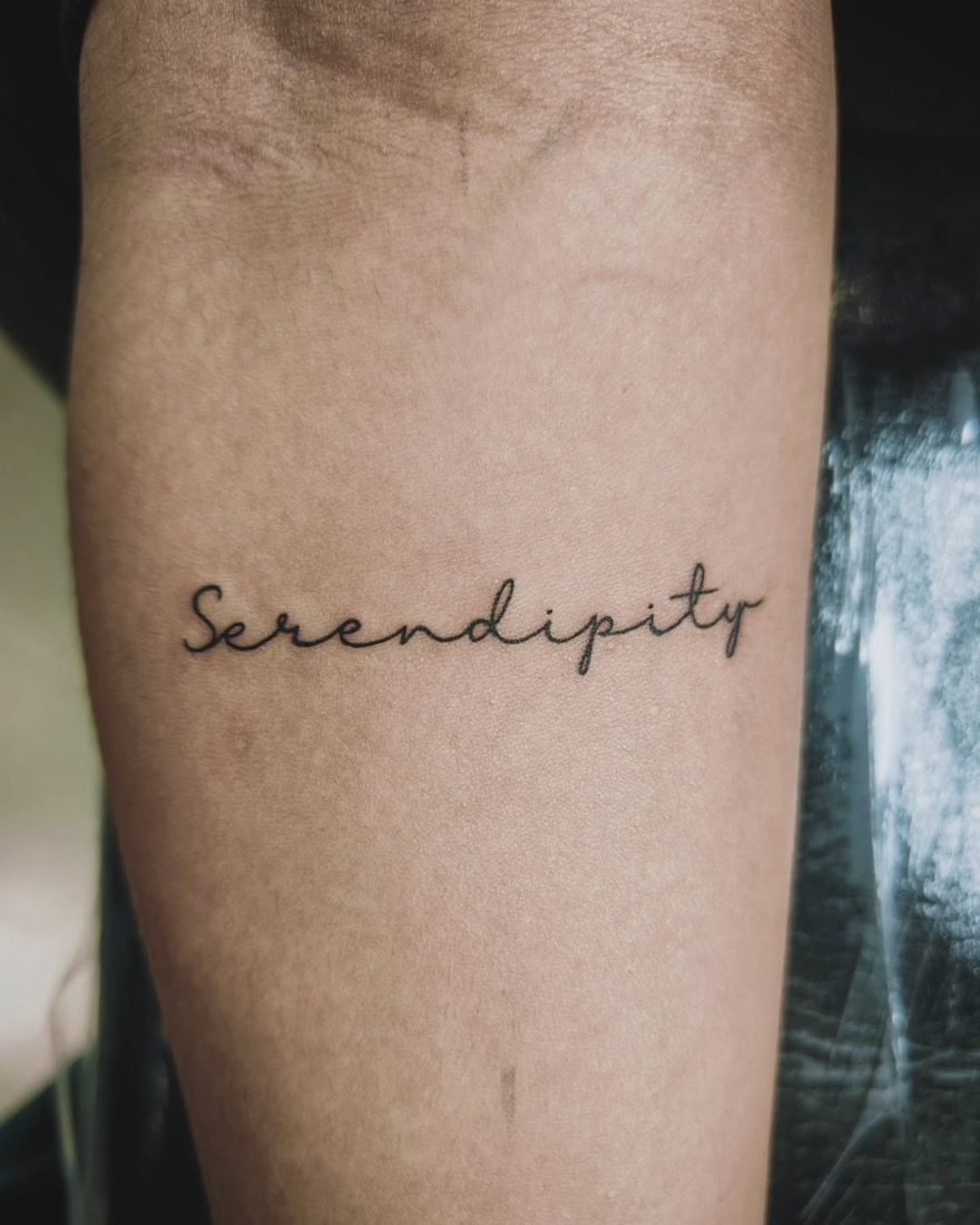 Serendipity Script Forearm Lettering — tattoo by Vulture Tattoos, Gurugram